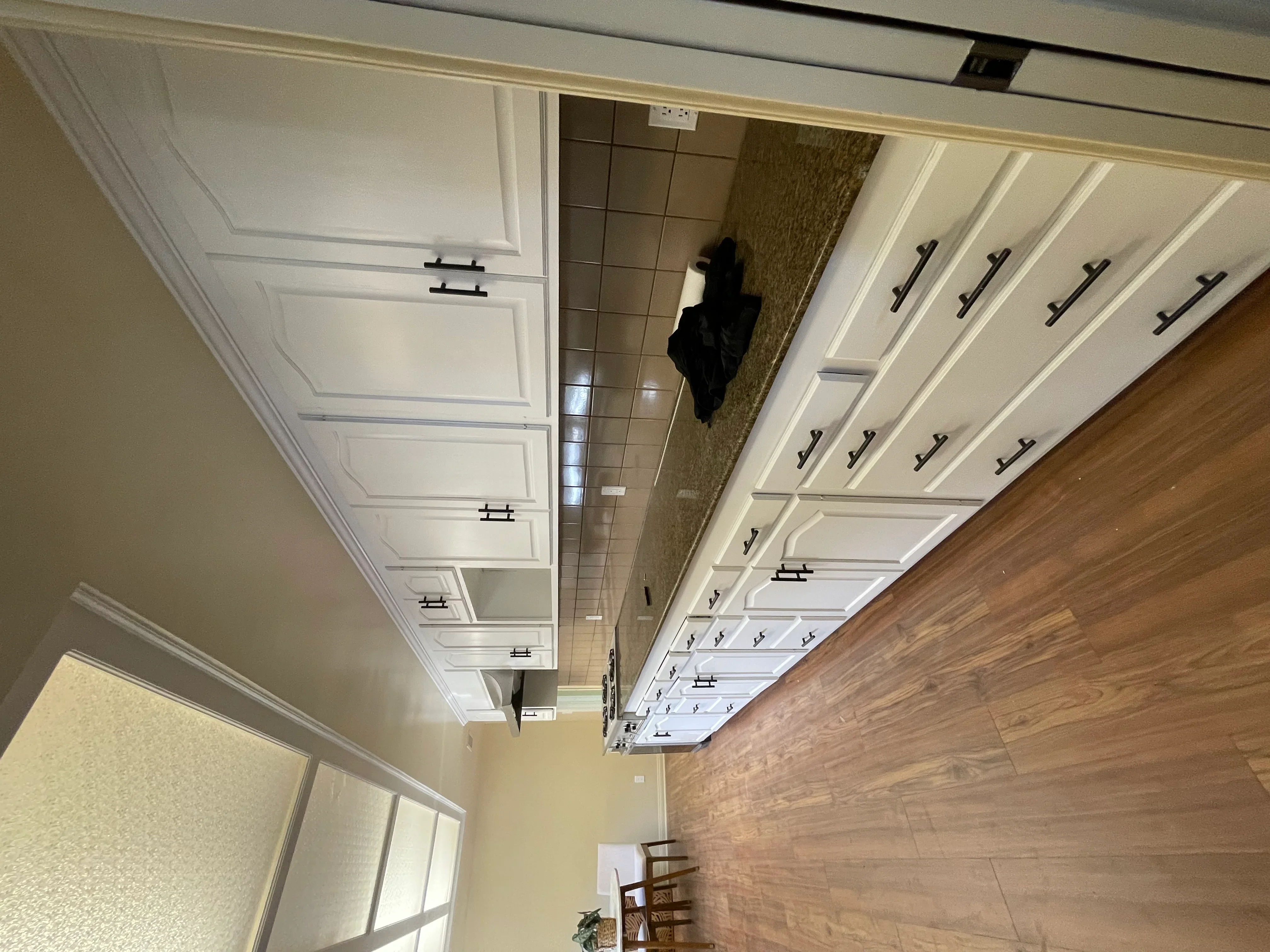 White painted kitchen cabinets with black handles and coffered ceiling with recessed panels