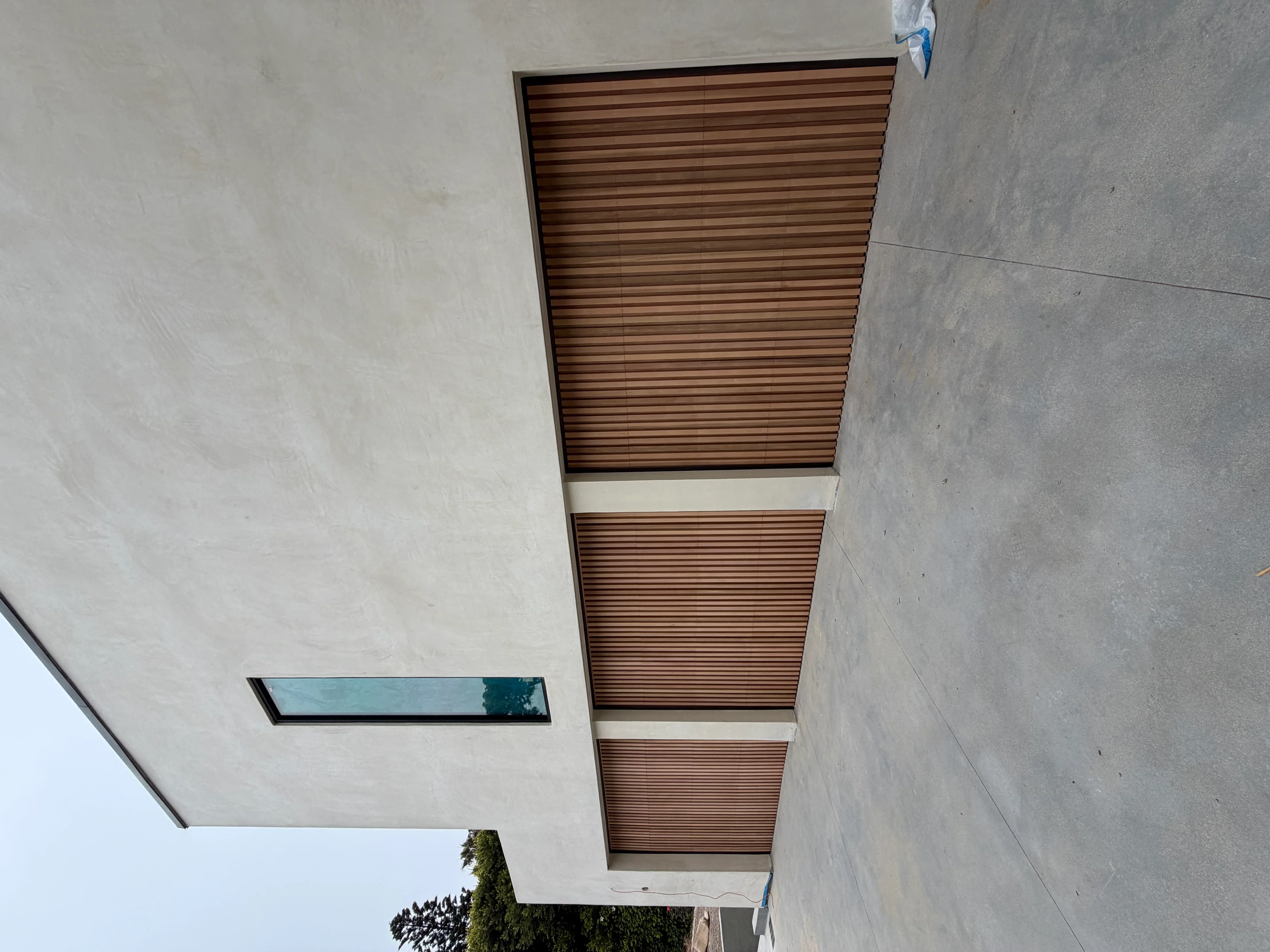 Wood slat soffit with horizontal cedar strips and white trim bands in ceiling opening