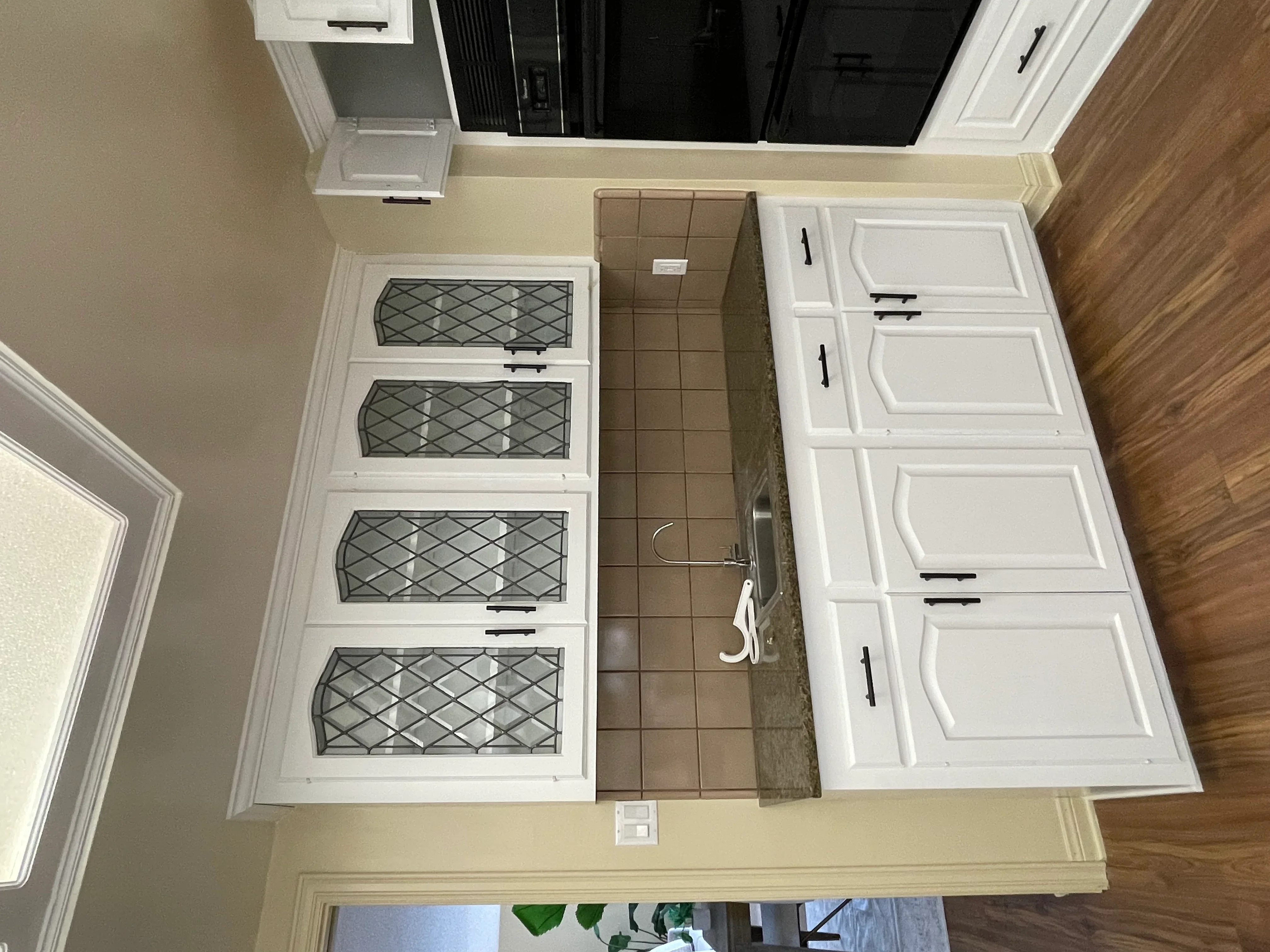 White painted kitchen cabinets with leaded glass diamond-pattern doors and black hardware