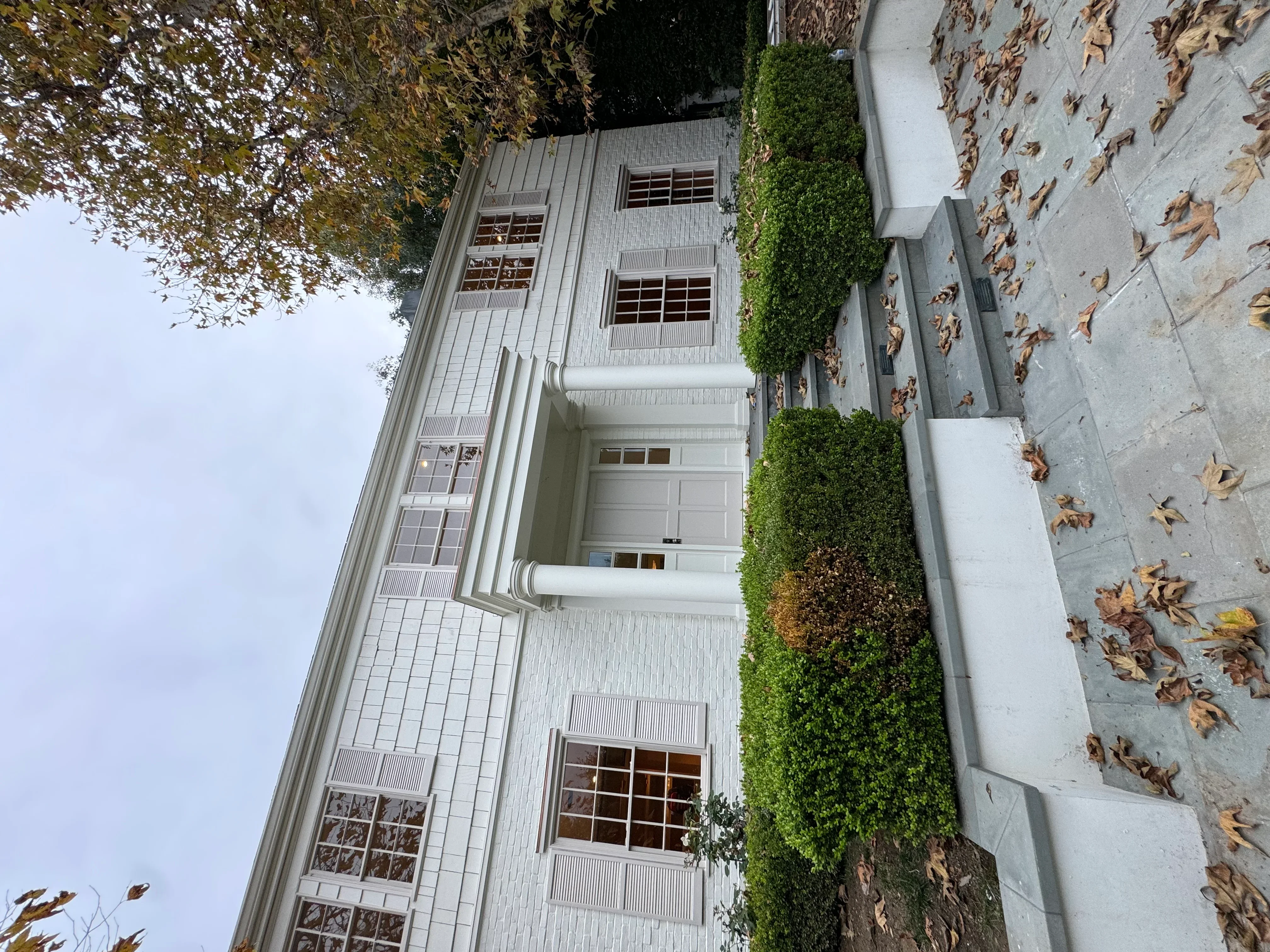 White painted residential home exterior with vertical siding, multiple windows, and white trim details