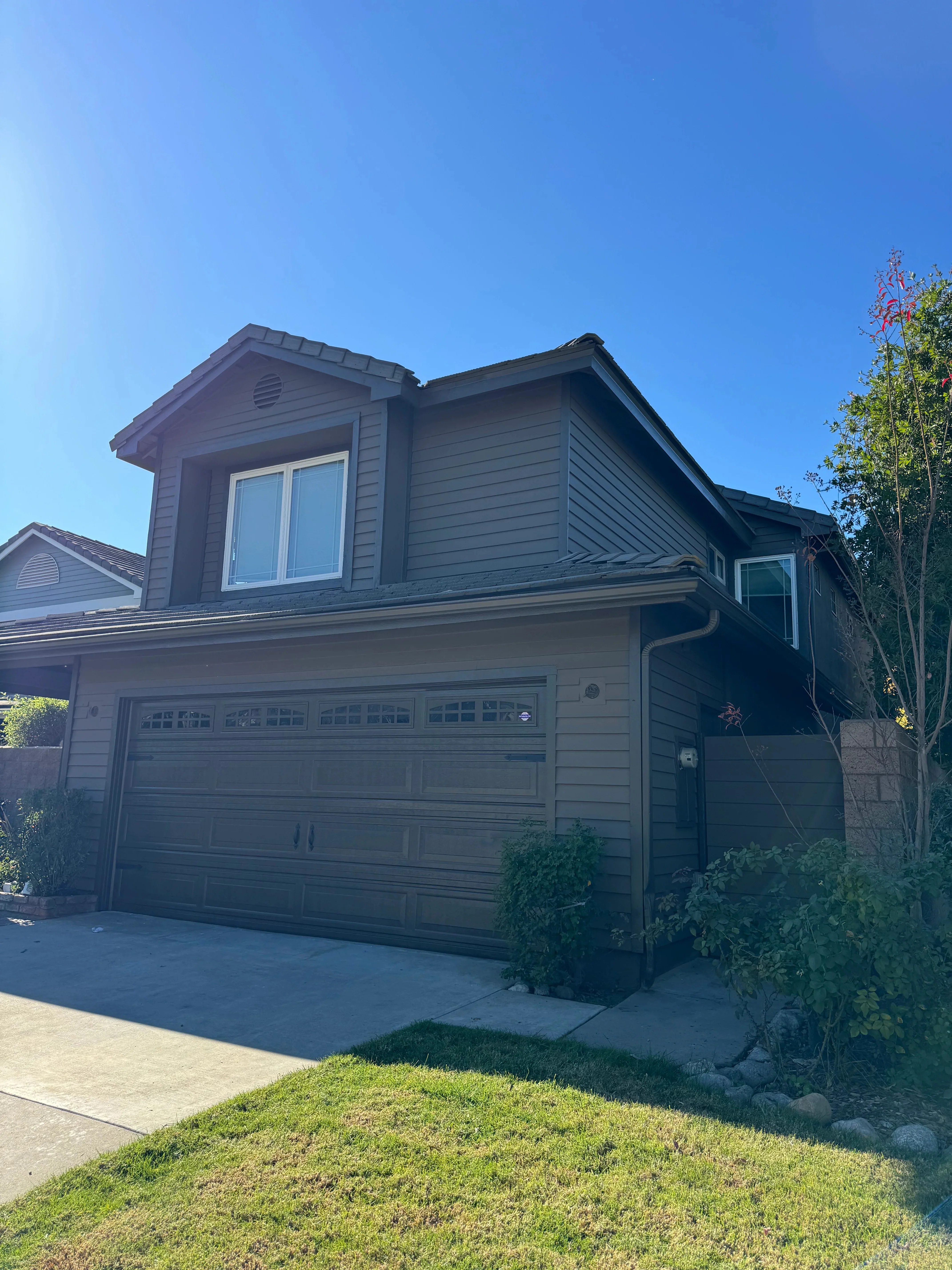 Two-story house with dark gray painted siding, trim, and garage doors