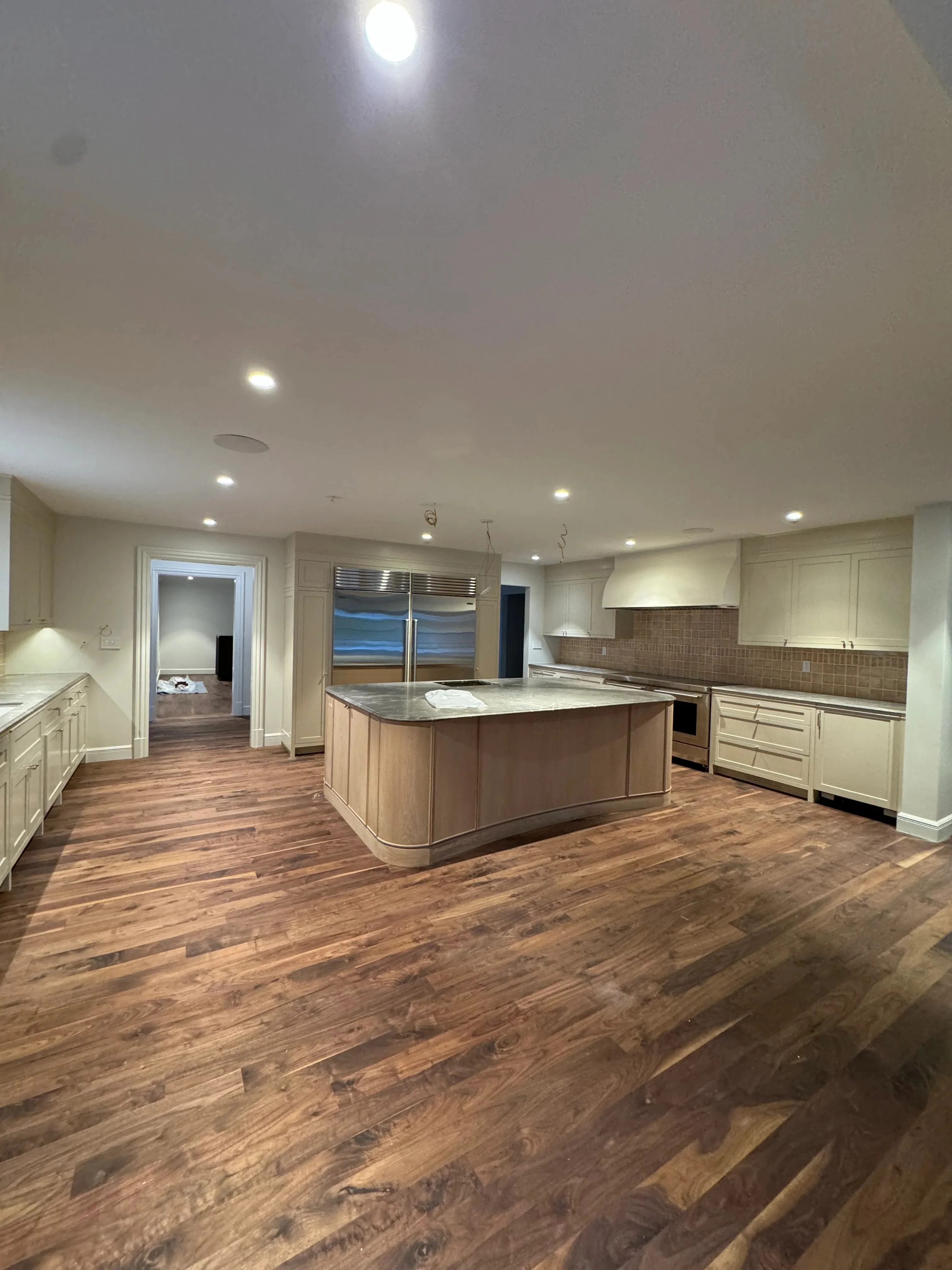 White painted kitchen cabinets, ceiling, and walls with recessed lighting and wood island